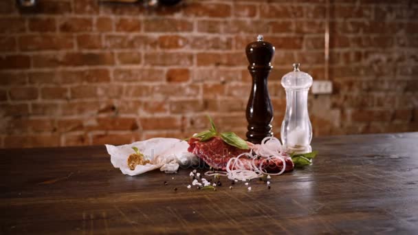 Masné výrobky. Šťavnaté maso hovězí steak na dřevěný stůl s sůl, černý pepř, nakrájenou cibuli. 4k
