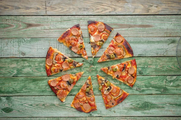 Fatias de pizza na mesa de madeira verde — Fotografia de Stock
