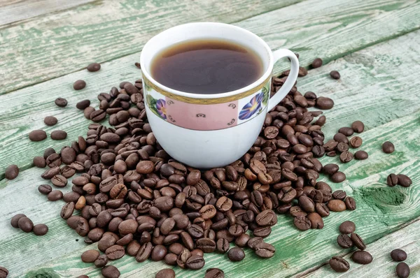 Xícara de café com grãos em mesa rústica verde. Textura de madeira — Fotografia de Stock