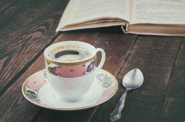 Kahve fincanı kaşığı ve kitap ile karanlık rustik tabloda. Ahşap arka plan