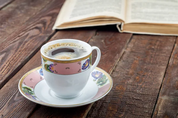 Coffee cup on dark wood table with book — Stock Photo, Image