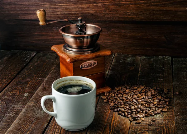 Xícara de café com moinho de café e grãos de café no fundo de madeira escura — Fotografia de Stock