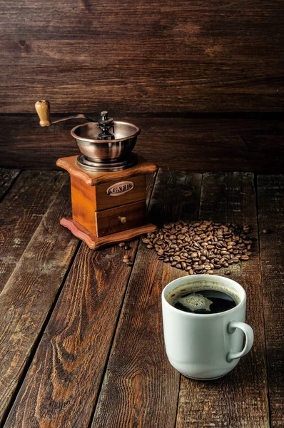 Xícara de café com moinho de café e feijão no fundo de madeira escura — Fotografia de Stock