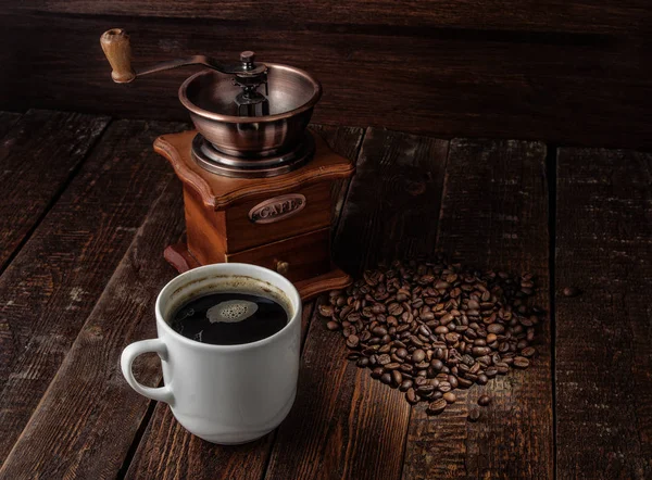 Coffee cup with coffee mill on dark wood table