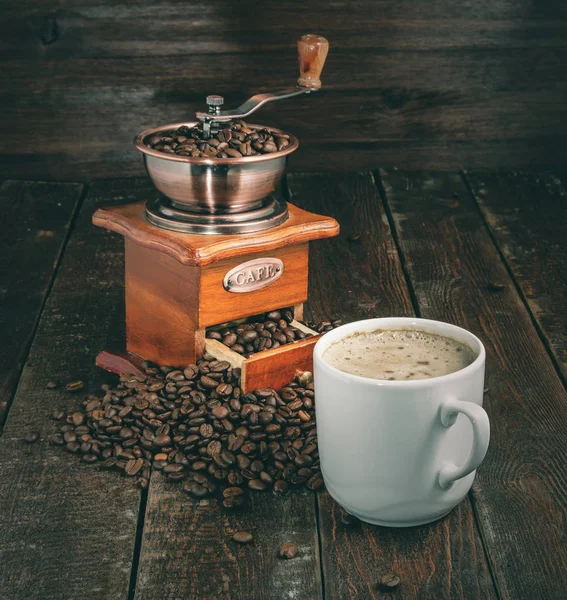Moinho de café e xícara com grãos no fundo escuro. Estilo retrô — Fotografia de Stock