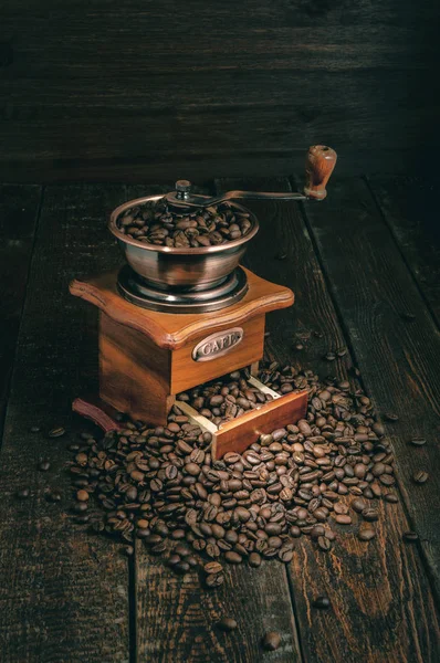 Moedor de café vintage com grãos de café no fundo rústico escuro — Fotografia de Stock
