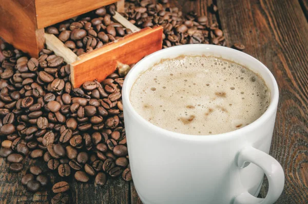 Młynek do kawy szczegół z filiżanki kawy i fasoli na rustykalne tabeli — Zdjęcie stockowe