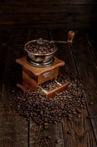 Moedor de café com grãos no fundo rústico escuro — Fotografia de Stock