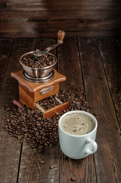 Xícara de café com grãos e moedor na mesa escura — Fotografia de Stock