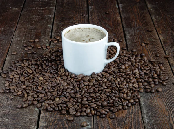 Caneca de café com grãos no fundo de madeira escura — Fotografia de Stock