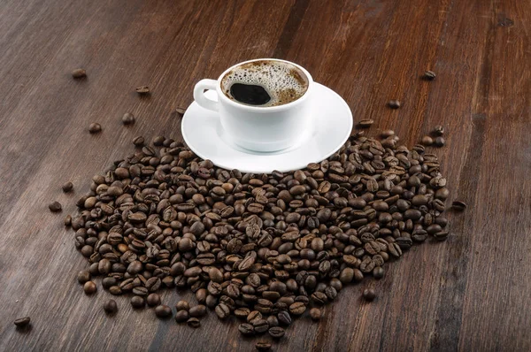 Xícara de café e feijão na mesa de madeira escura — Fotografia de Stock