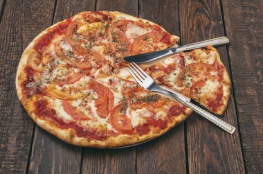 Koyu ahşap masada mozarella soslu lezzetli pizza margaritası.