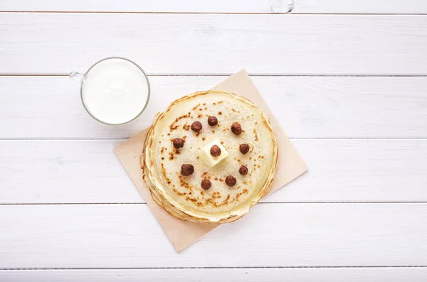 Crêpes au lait en verre, noisette et beurre sur fond blanc — Photo