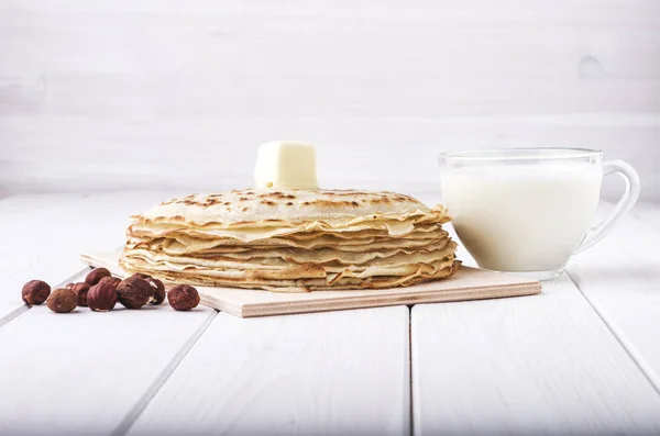 Pfannkuchen mit Milch im Glas, Haselnuss und Butter auf Holzgrund — Stockfoto