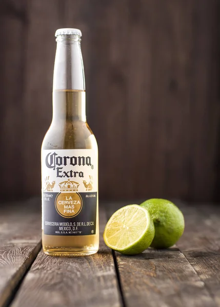 Foto editorial de garrafa de cerveja extra Corona com limão sobre fundo de madeira escura — Fotografia de Stock