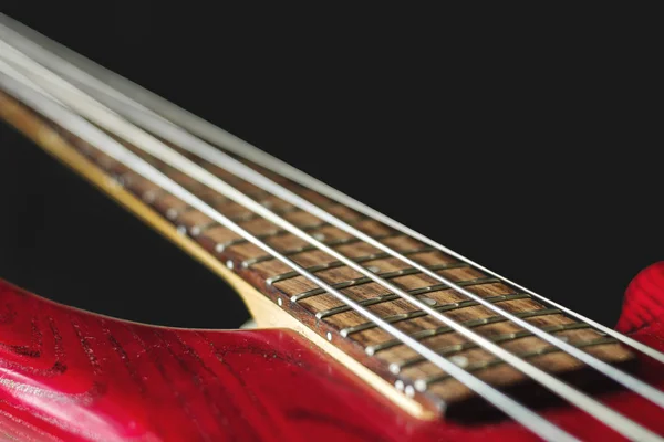 Bajo eléctrico rojo con cuatro cuerdas sobre fondo oscuro —  Fotos de Stock