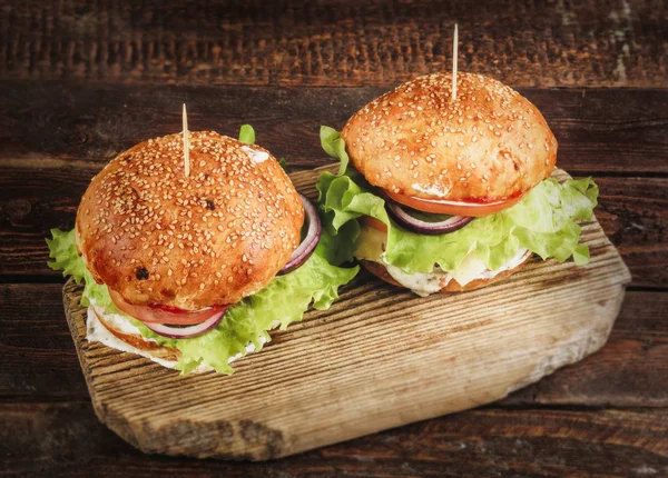 Delicious burgers on wooden cutting board. Top view — Stock Photo, Image