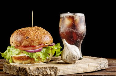 Ev yapımı burger beef ve bardak soğuk kola ve sarımsak ahşap plaka üzerinde