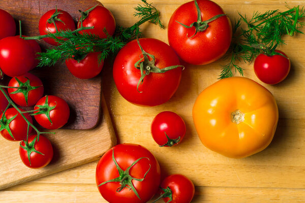свежие красные и желтые помидоры с укропом на деревянном фоне

