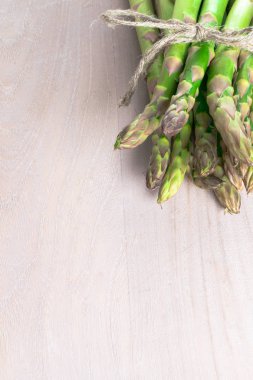 kamçı ile gri ahşap arka plan üzerinde ham taze yeşil kuşkonmaz grup