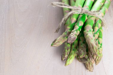 kamçı ile gri ahşap arka plan üzerinde ham taze yeşil kuşkonmaz grup