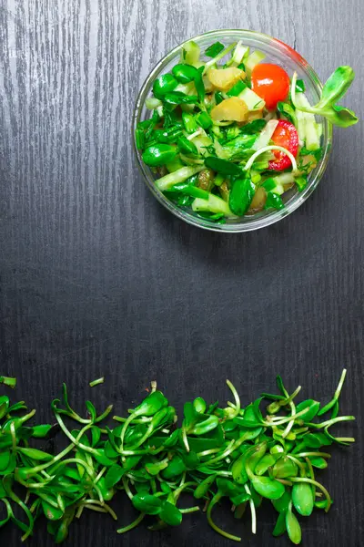 Verdes crus frescos no fundo escuro com tigela com salada — Fotografia de Stock