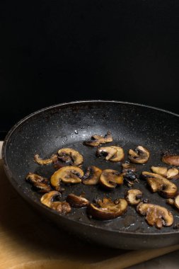 Ahşap masada kızartma tavasında kızarmış mantar. Akşam yemeği için tabak. Görüntüyü kapat