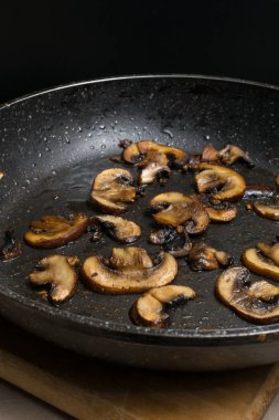 Ahşap masada kızartma tavasında kızarmış mantar. Akşam yemeği için tabak. Görüntüyü kapat