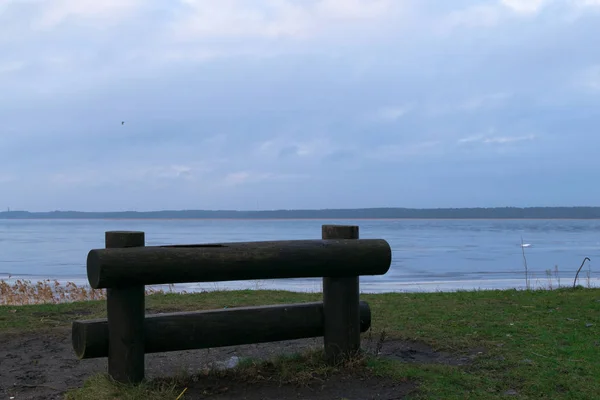 Viejo banco de madera en la hierba con vista al agua y el cielo — Foto de stock gratis