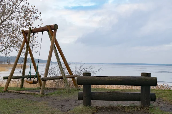 Viejo banco de madera en la hierba con vista al agua y el cielo. Allá en el salvaje azul . — Foto de Stock