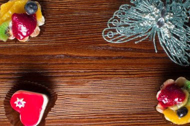 Gümüş kelebek ile dekore edilmiş ahşap arka plan üzerinde küçük lezzetli meyve kek