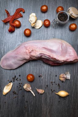 Bir arka plan siyah yakın çekim üzerinde bir kesme tahtası üzerinde sebze - kereviz, siyah ve kırmızı biber, sarımsak, soğan, çiğ sığır eti veya domuz eti diliyle yatıyor