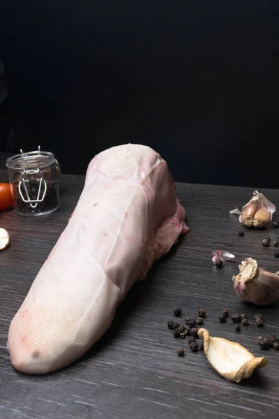 Carne cruda o lengua de cerdo con verduras- apio, pimienta, ajo, cebolla, se encuentra en una tabla de cortar, sobre un fondo negro primer plano —  Fotos de Stock