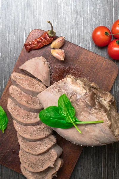 Carne de vaca fervida, língua de porco com tomates, folha de manjericão, tiro estúdio, isolado no fundo de madeira . — Fotografia de Stock