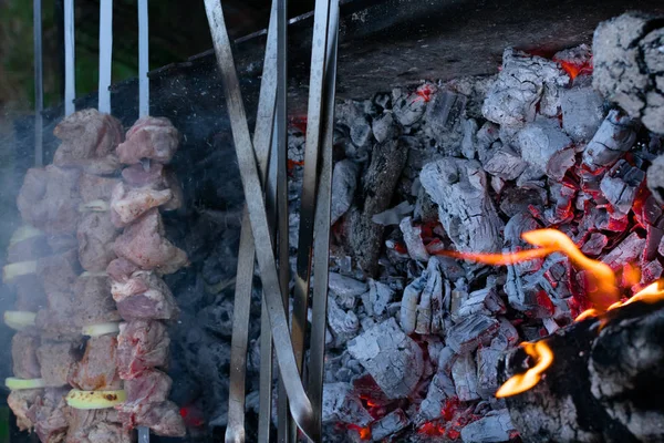 Shish kebab em espeto de metal está assando na grelha. Festa de churrasco. Close-up. Churrasco com cebola. Temporada de Barbucue — Fotografia de Stock
