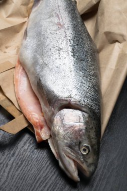 Ham taze alabalık kağıt çanta pişirme için hazırlıklar üzerinde siyah bir arka plan görüntüsünü kapatmak