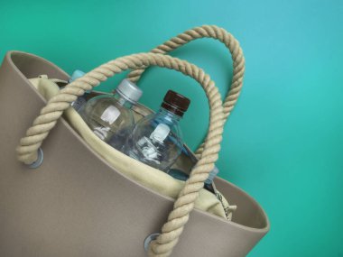 Mavi arka planda bir eco torbasında basit plastik şişeler, geri dönüşüm konsepti