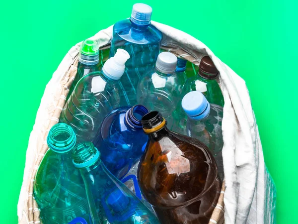 Botellas de plástico simples en una bolsa ecológica sobre un fondo verde, concepto de reciclaje — Foto de Stock