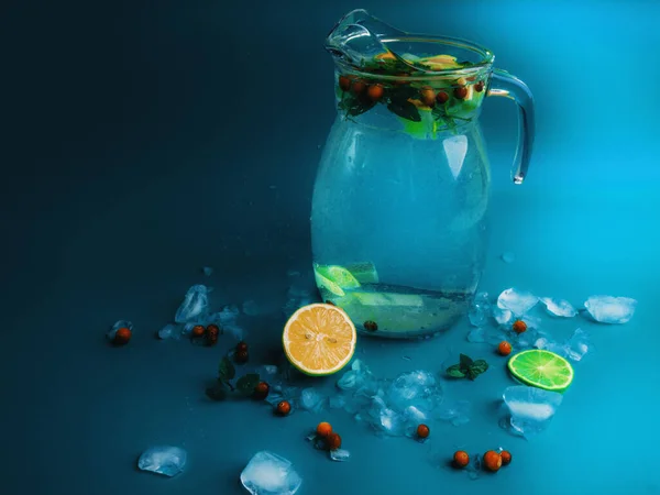 Фруктові та ягідні лимонадні напої, освіжаючі напої наливають воду, у скляні банки, зі свіжою журавлиною, скибочками лимона та лайма на синьому фоні — стокове фото