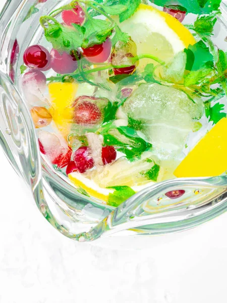 레몬 조각, 박하 잎, 붉은 딸기와 얼음 조각, 유리 주스 를 넣은 레모네이드 주전자. 복사 공간으로 본 — 스톡 사진