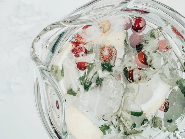 Suco de limonada com limão, limão, folhas de hortelã, cranberries. Bebida fresca de gelo de verão, água de desintoxicação, cubos de gelo e jarro de vidro — Fotografia de Stock