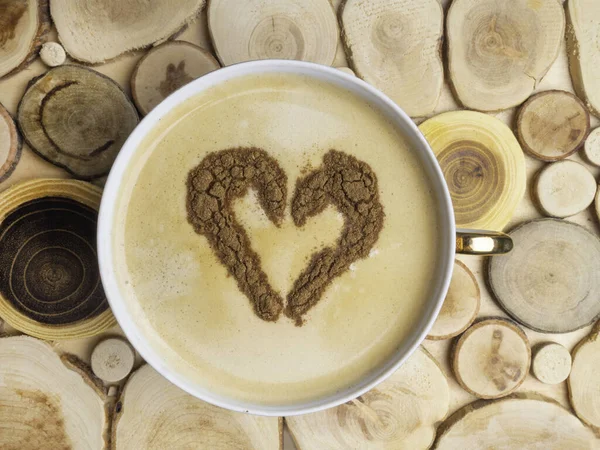 Forma de corazón, símbolo del amor en el café blanco caliente, signo del amante del polvo de canela, en la superficie de madera — Foto de Stock
