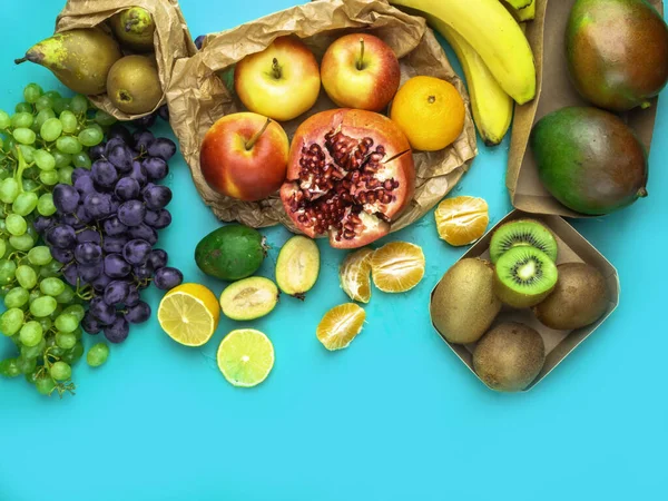 Fruits and vegetables rich in antioxidants, vitamin and fiber on blue background. Zero waste food shopping, eco natural paper bags Flat lay style