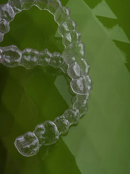 Dientes de ortodoncia clara alineador para enderezar los dientes en la superficie verde — Foto de Stock