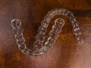 Görünmez diş telleri diş tellerini düzenlemek için plastik diş tellerini ayarlar. Turuncu arka planda ortodontik geçici düzelticiler