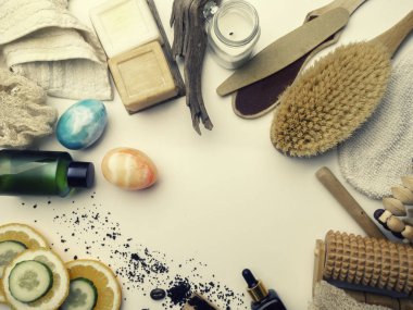 Beyaz arka planda kaplıca ve cilt bakımı konsepti. Mesaj için yer var. Üst Manzara. Doğal malzemeli vücut kahvesi fırçası, salatalık ve portakal dilimleri, sabun, serum, yağ, taş, masaj aleti.