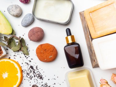 Doğal organik malzemelerden kişisel bakım ürünleri. Modern tıp, eczacı. Butters, sabun, serum, fırça, portakal dilimleri, avokado, masaj için taşlar düz serili.