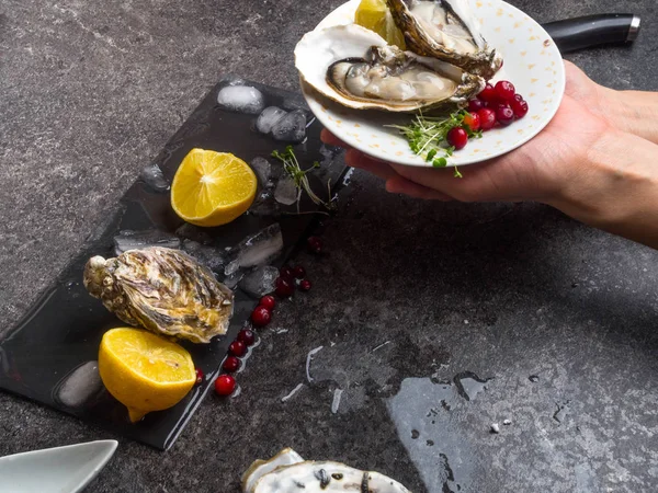 Open oester in een mensenhand, tegen een achtergrond van open oesters, close-up. — Stockfoto