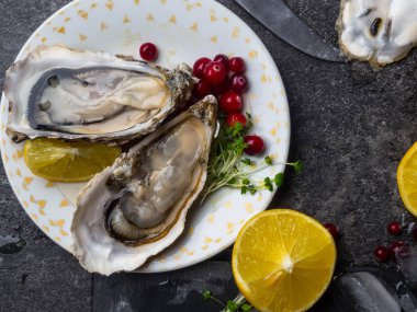 İstiridye kalbi tabakta limon, kızılcık, mikro yeşillik, bıçak, mermer kabuk şeklinde.