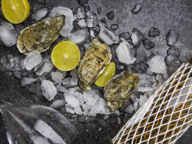 Taze istiridye, buzlu ve limonlu şarap, taş masanın üzerinde bardak. Üst görünüm